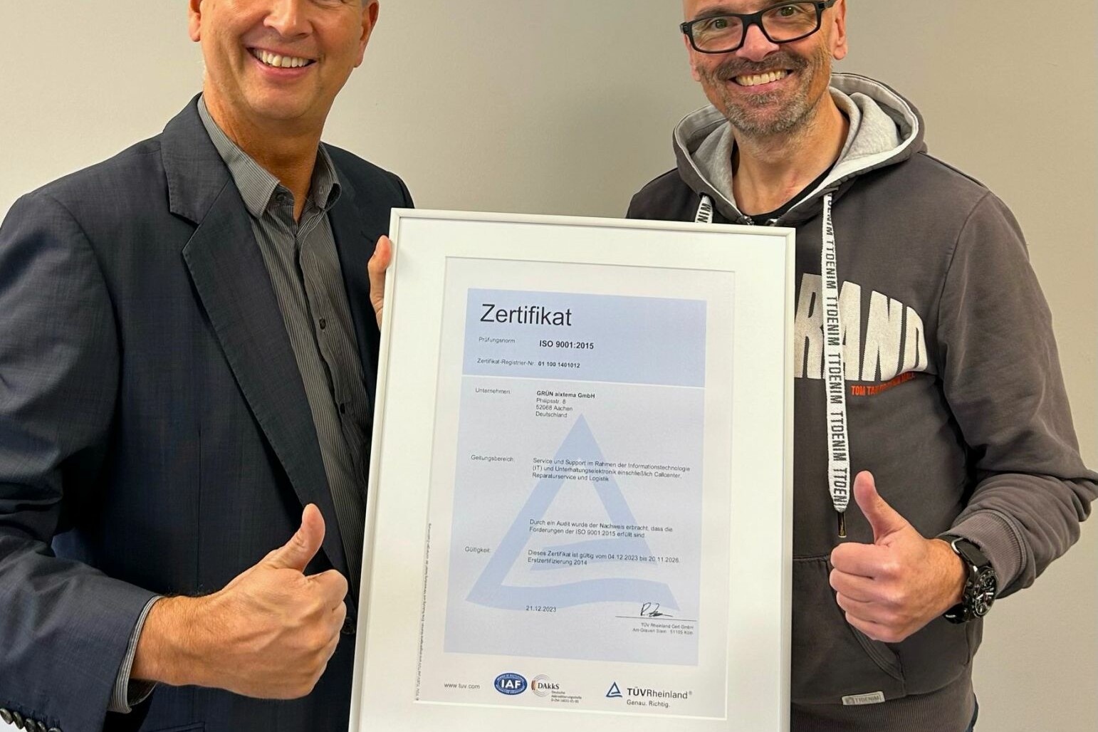 Der TÜV Rheinland, vertreten durch Ralph Freude (links), überreicht Oliver Roßbruch, CEO der GRÜN aixtema GmbH, das DIN ISO 9001:2015 Zertifikat.